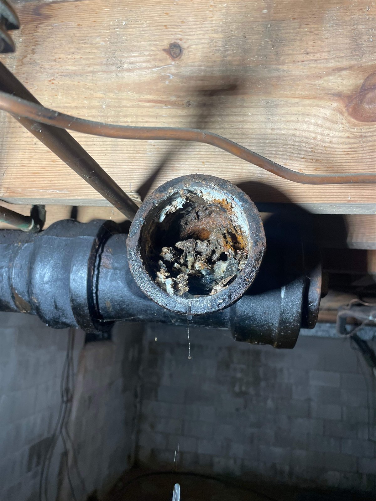 Severe scale buildup inside a corroded cast iron sewer pipe, a common precursor to a collapsed or broken line.