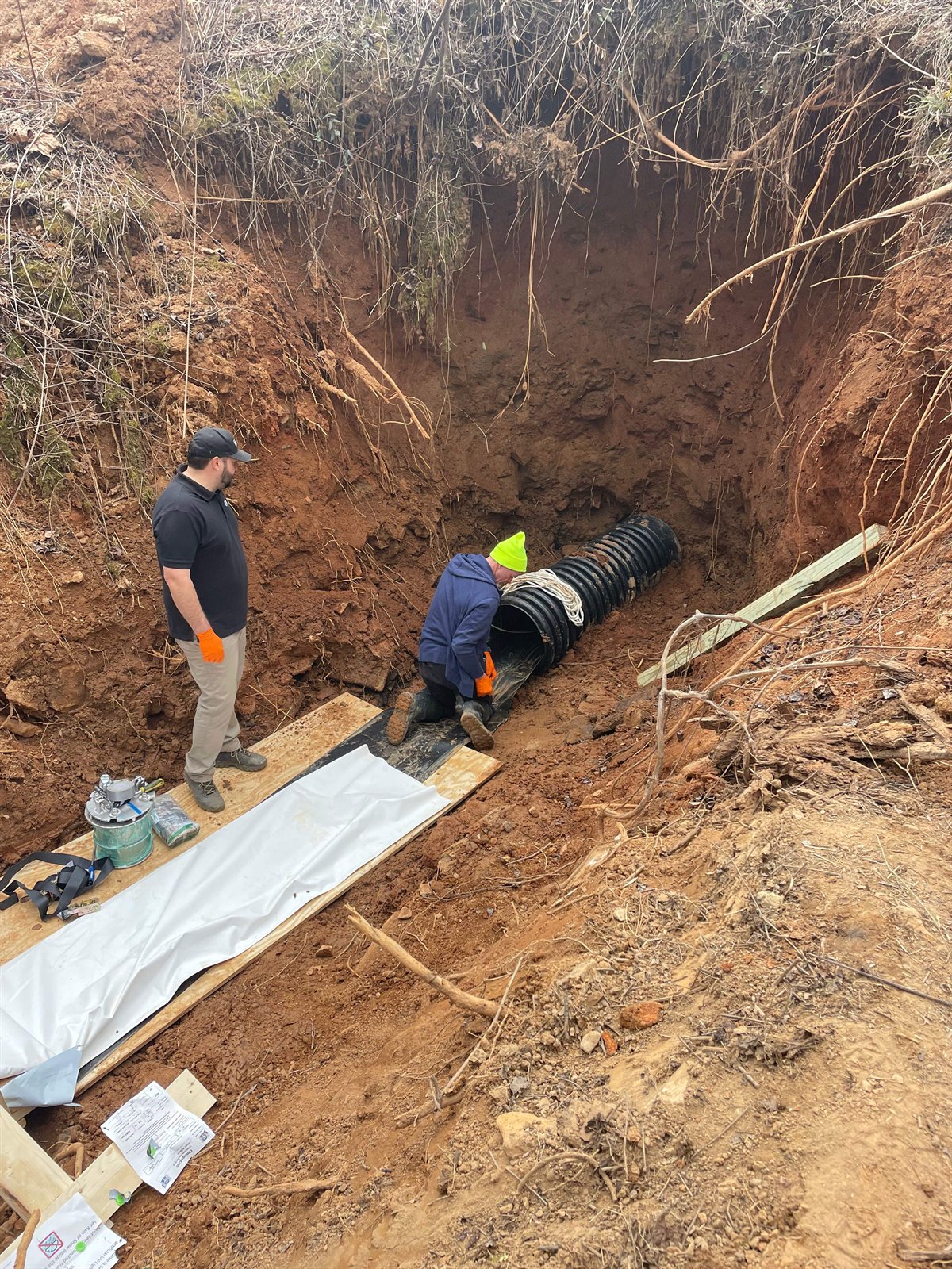LiningWorks crew setting a large-diameter storm drain pipe in an excavated trench.