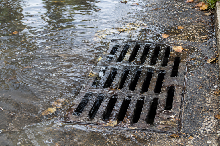 LiningWorks Trenchless Pipe Repair & Sewer Pipe Lining inspects frequent street flooding from a blocked storm drain.