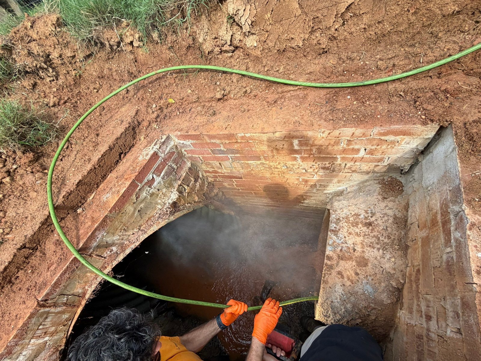 LiningWorks technician hydro jetting a brick storm drain line through an open access point.