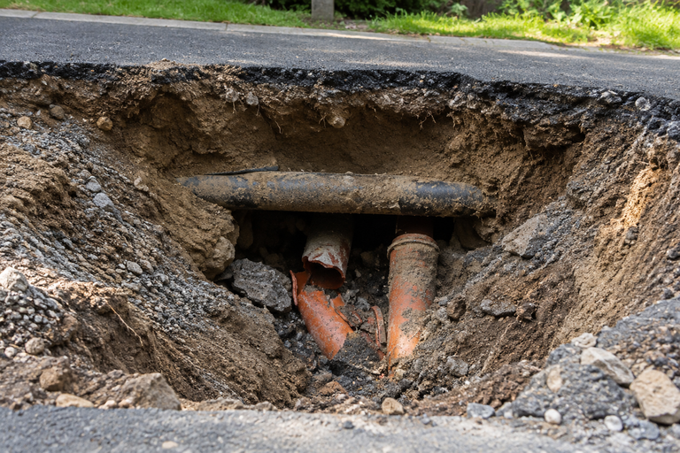LiningWorks Trenchless Pipe Repair & Sewer Pipe Lining investigating a yard sinkhole with exposed, collapsed sewer pipes.