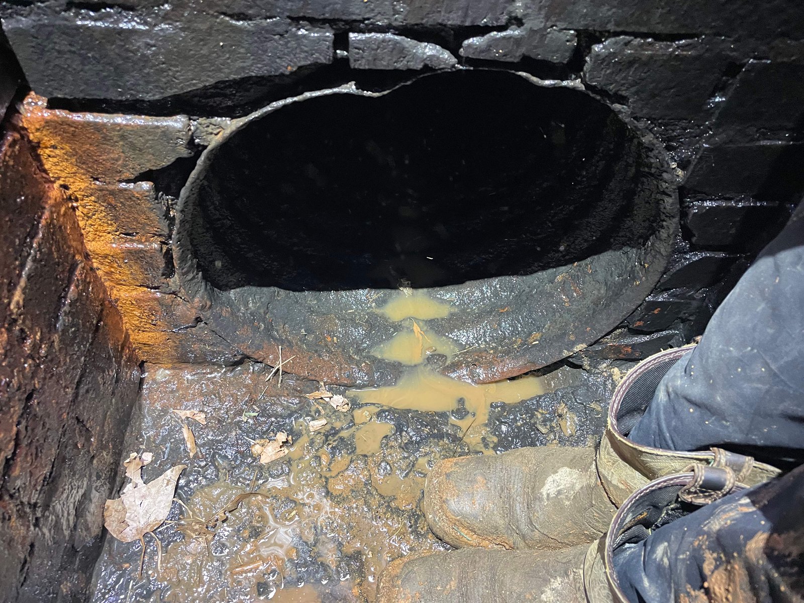 Isolated pipe connection failure in a brick storm drain structure, the kind of localized defect suited to spot repair.